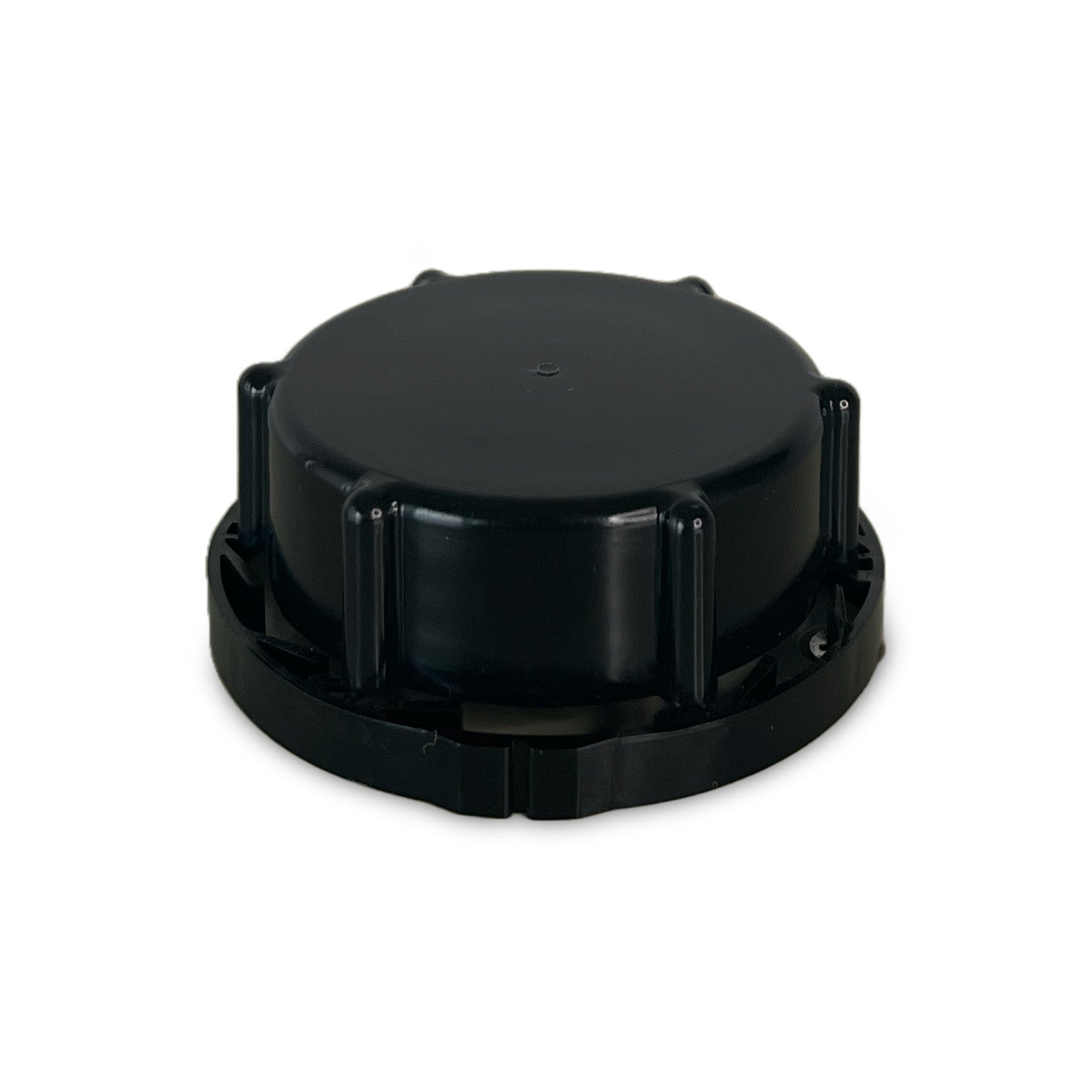 A black, round plastic cap with ridged edges and raised grip tabs, photographed on a white background.
