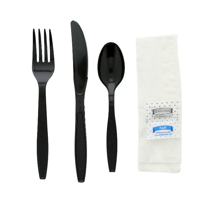 The 6-in-1 Cutlery Kit includes a black plastic fork, knife, and spoon arranged beside a folded white napkin with small black dots, plus pepper and salt packets. Case of 250.