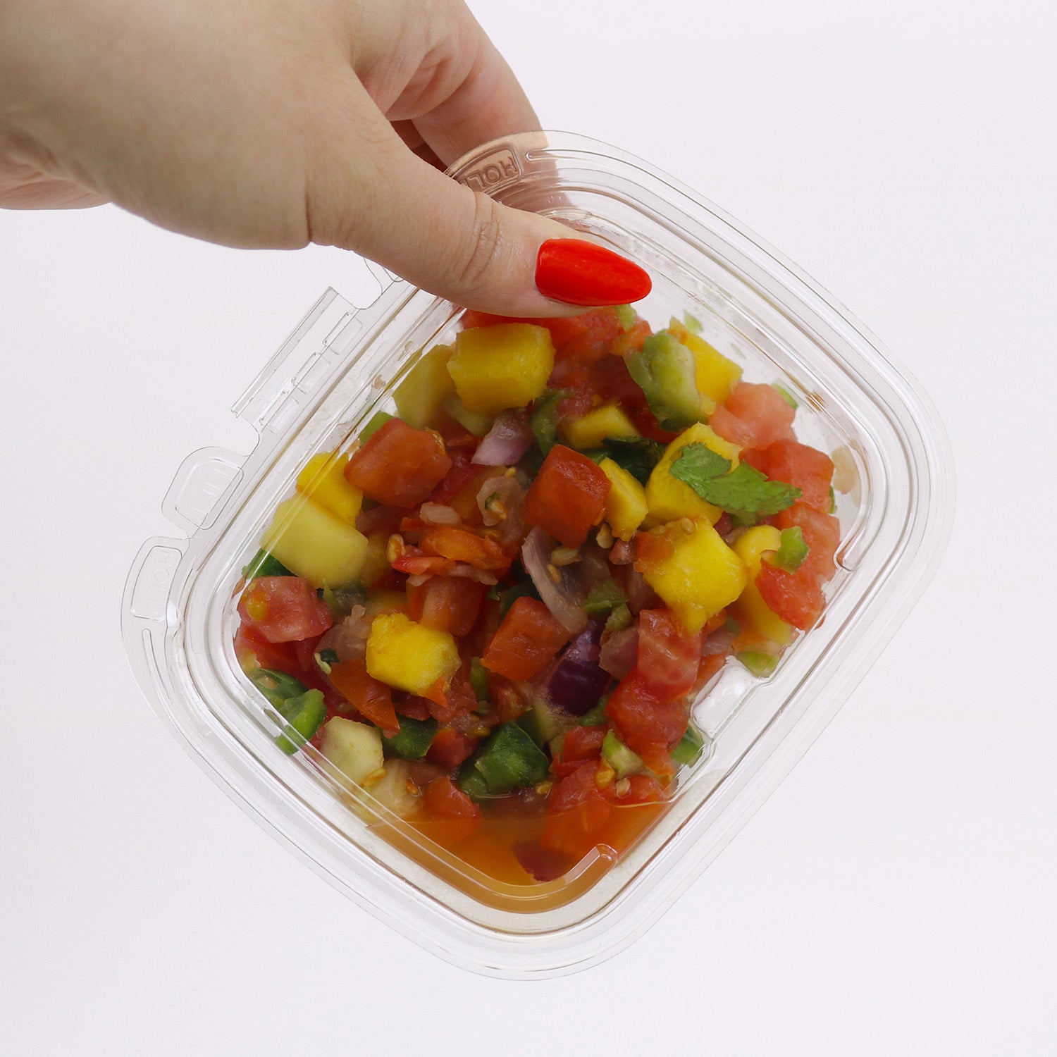 A hand with red-painted nails holds an 8 oz. Tamper-Evident Crystal Seal container (case of 210), filled with colorful salsa, against a white background.
